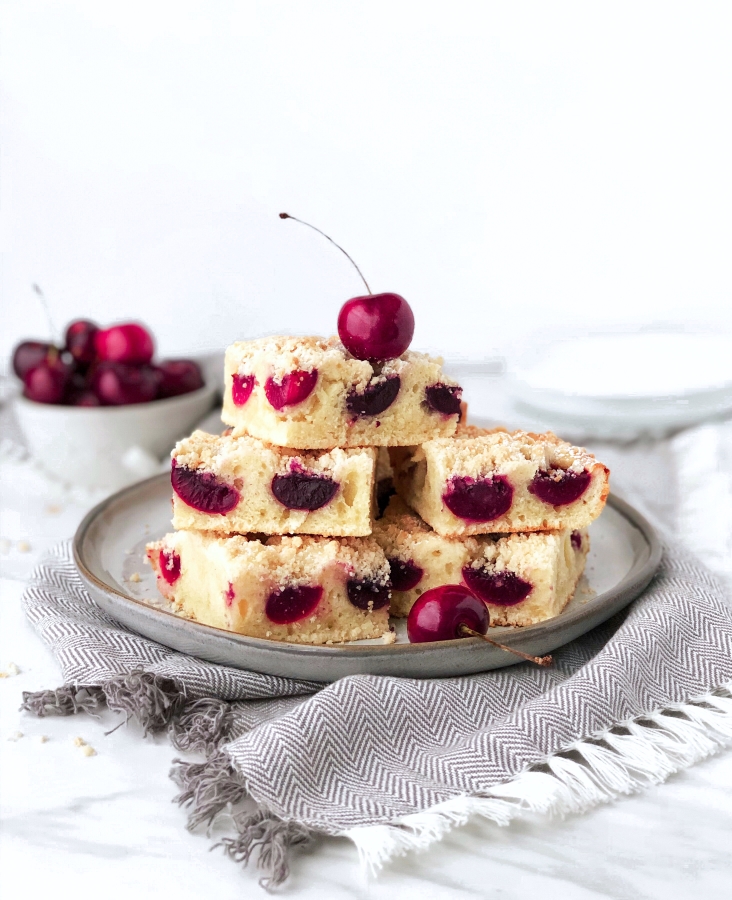 Bars of cherry fruit cake on the plate. Fresh cherries in the bowl in the background