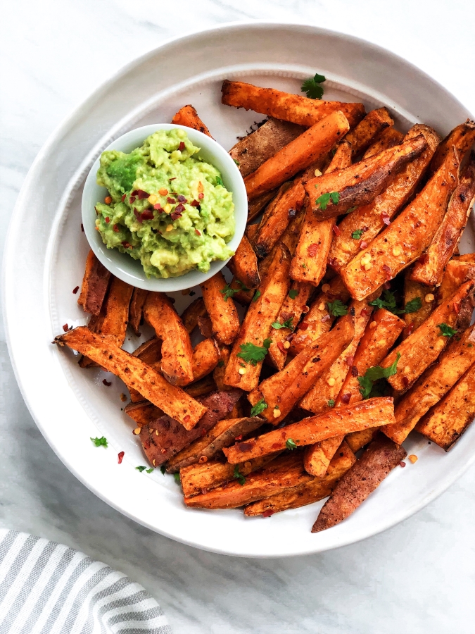 sweet potato fries in a white plate, with guac 