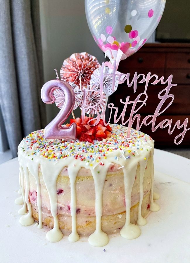 Strawberry Vanilla Layer Cake on a white board, number two candle and cake toppers